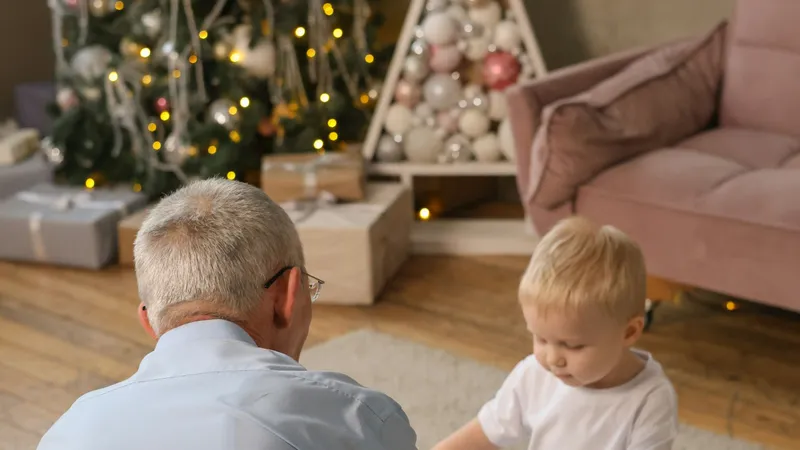 Dziadek z wnukiem przy prezentach pod choinką
